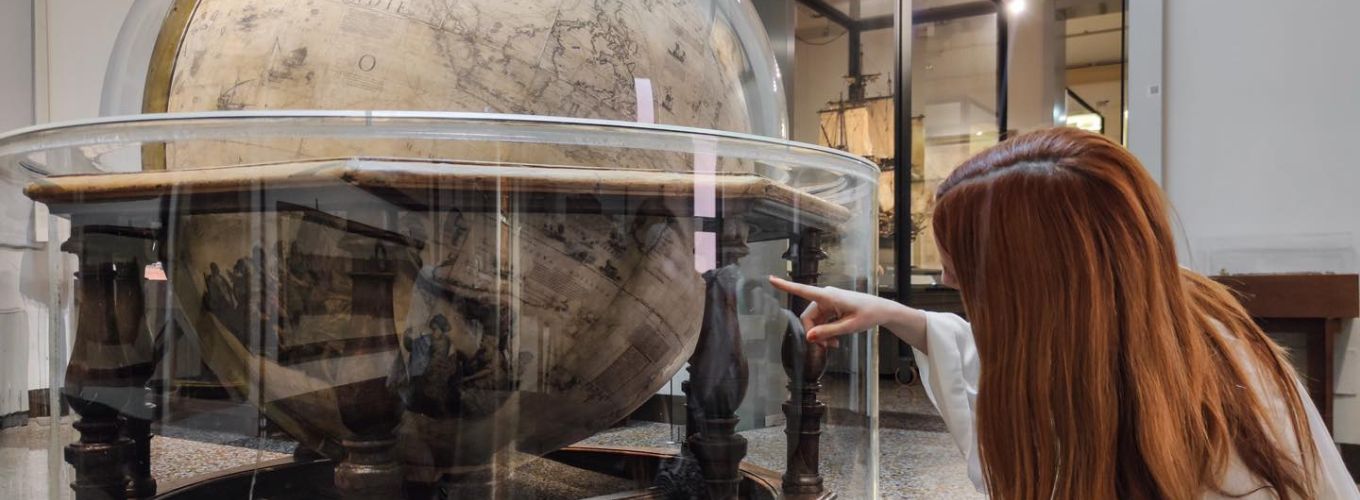 Visitor pointing to a globe in the Museum of Palazzo Poggi