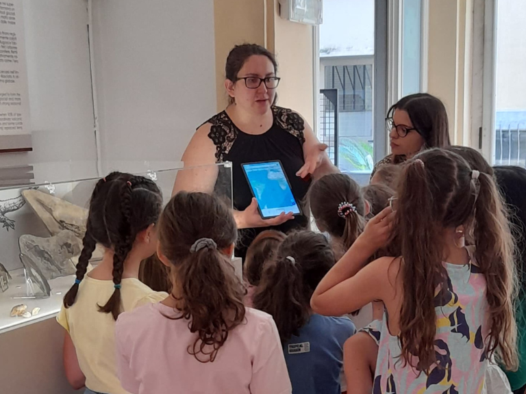 Immagine per Famu 2025 con bambini che ascoltano una visita guidata alla Collezione di geologia